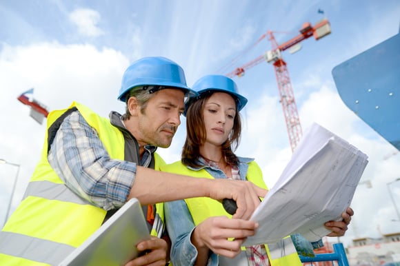 Worker reviews clipboard for risk management in construction under a clear sky.