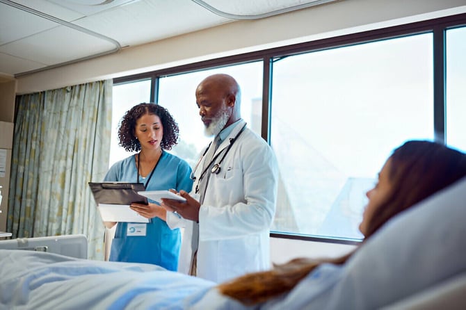  A doctor and nurse reviewing a patient's medical file in a hospital room, discussing an incident report in healthcare 