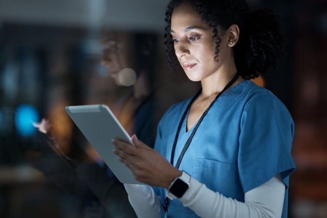  A nurse reviewing patient data on a tablet, emphasizing the importance of incident reporting in healthcare. 